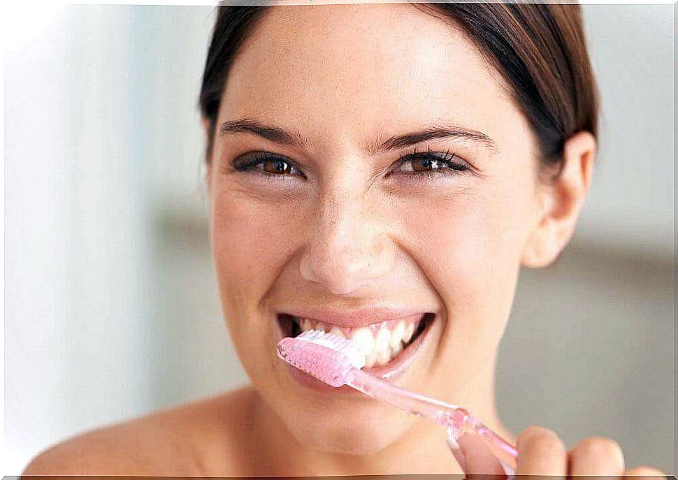 The woman is brushing her teeth to prevent tooth decay