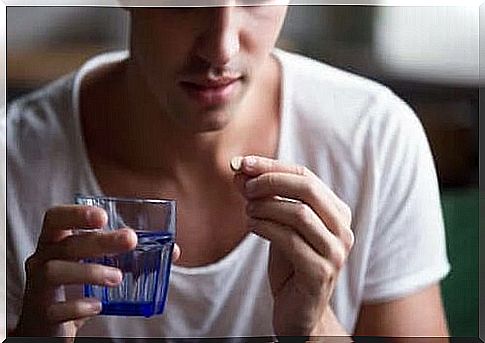 The man holds a tablet and a glass of water in his hand