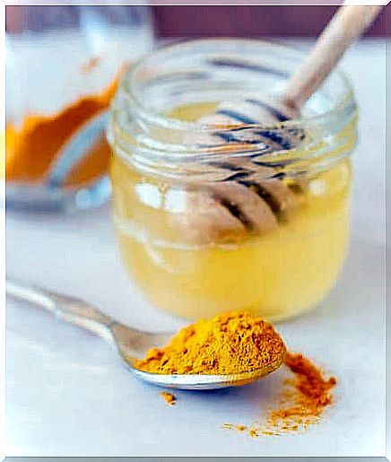 Turmeric on a spoon and a jar of honey